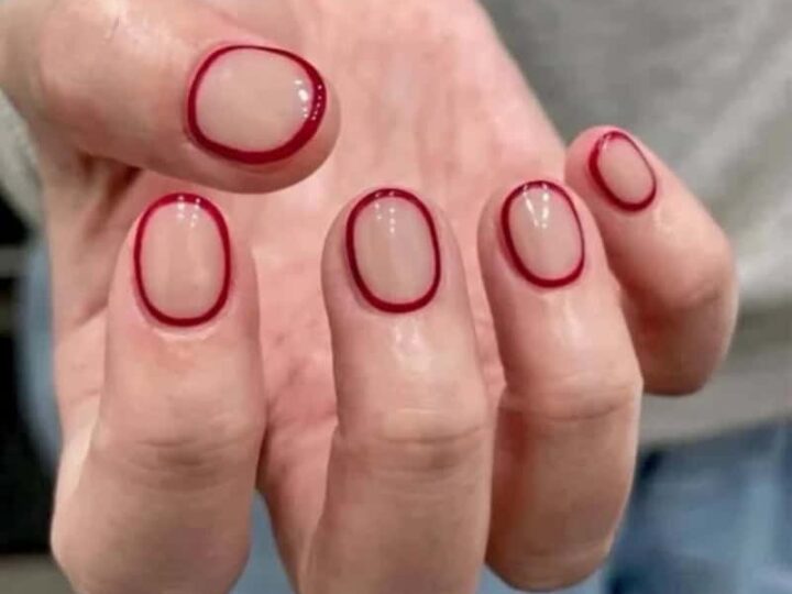 Hand with red nail polish and a red ring around each fingernail.
