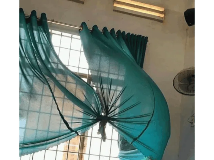 A person is holding a large, blue, inflatable dolphin in a room.