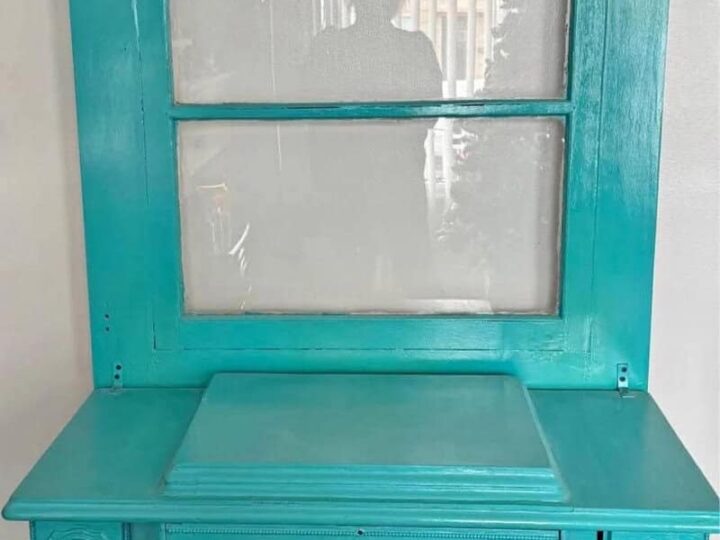A turquoise vintage sewing machine table with a mirror and decorative items.