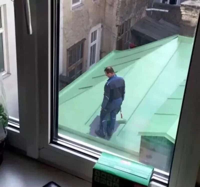 Man on green roof seen through window, part of funny home improvement fails.