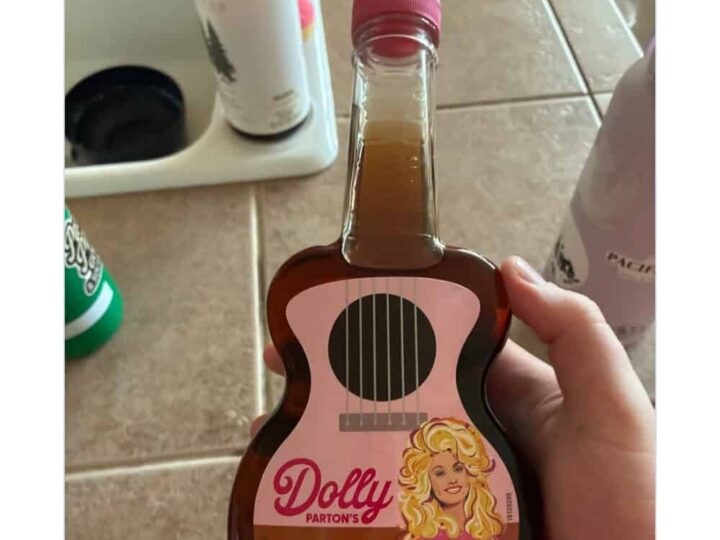 Hand holding a Dolly Parton syrup bottle shaped like a guitar.