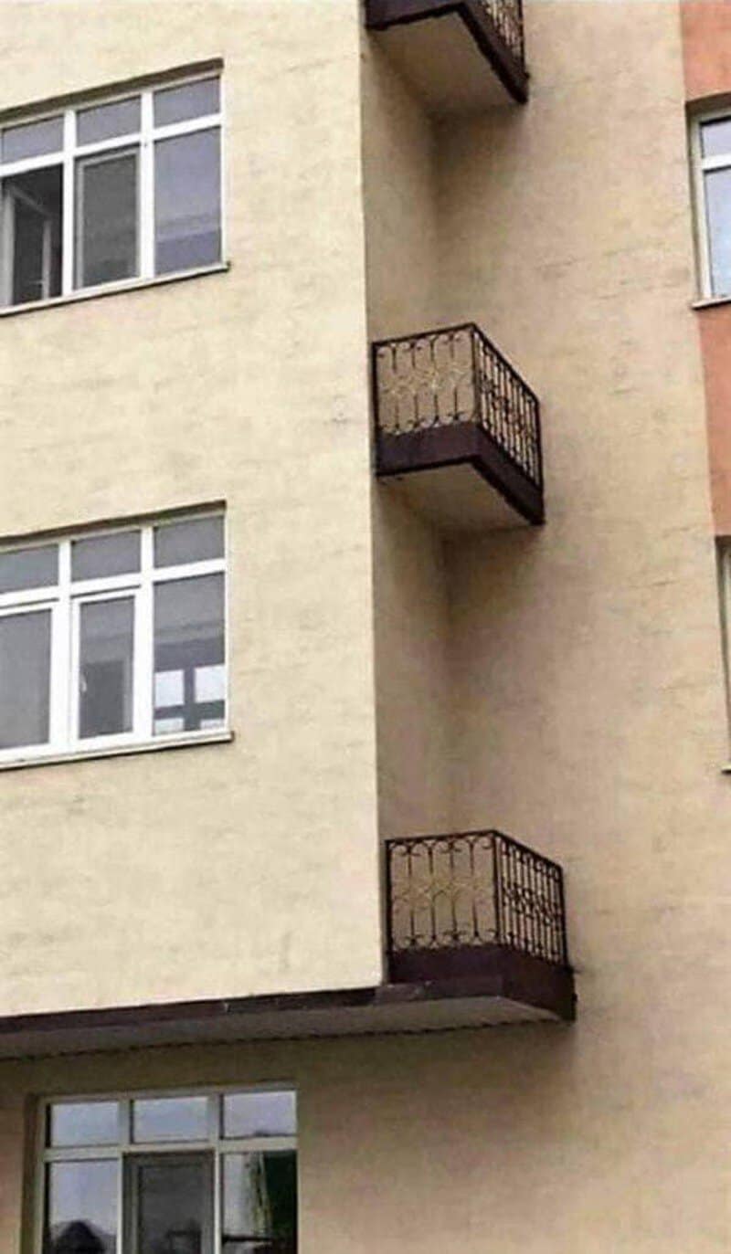 Two small balconies on a beige building, one above the other, with no access doors.