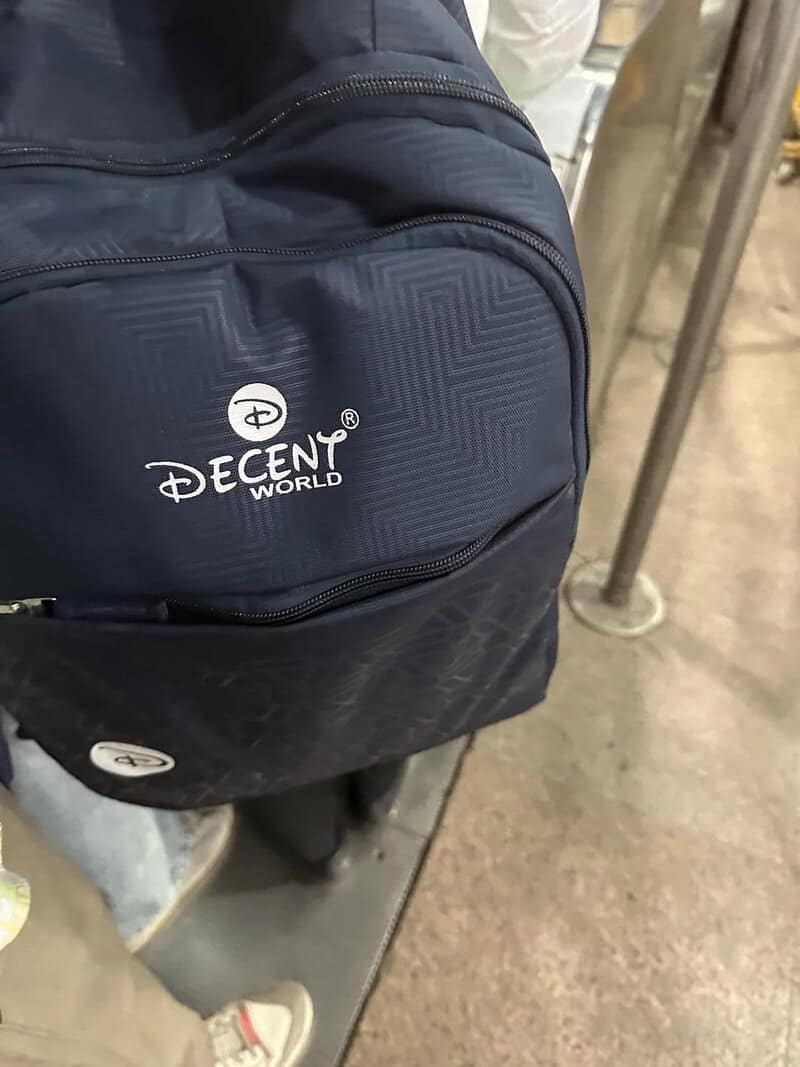 Backpack with Decent World logo on it, in a store or warehouse setting.