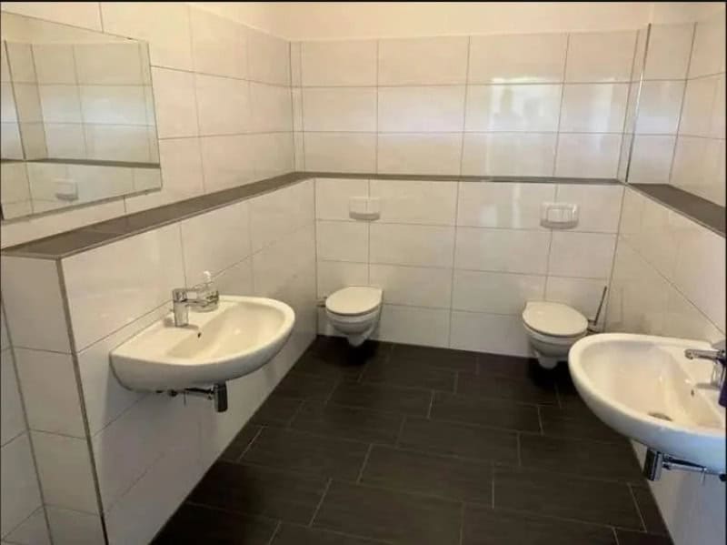 Empty public restroom with two sinks and two toilets.