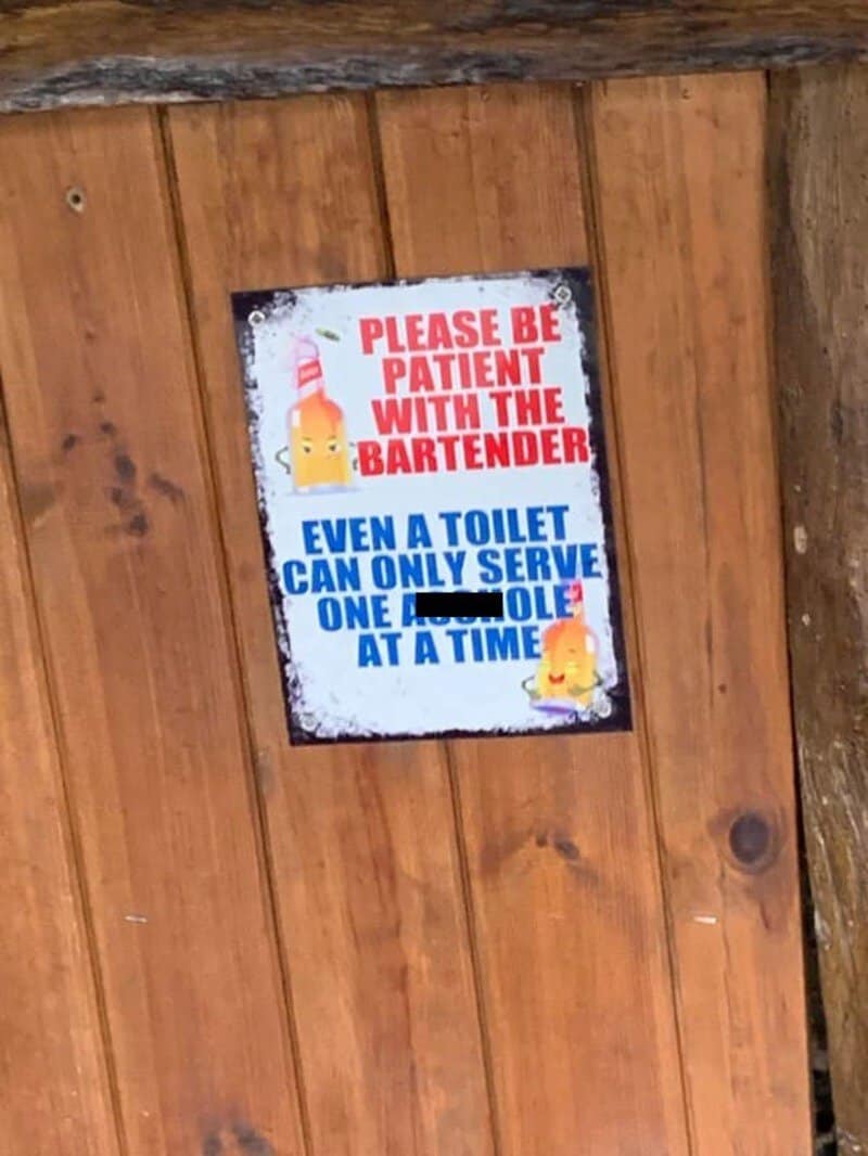 Sign reading 'Please be patient with the bartender. Even a toilet can only serve one at a time.'.