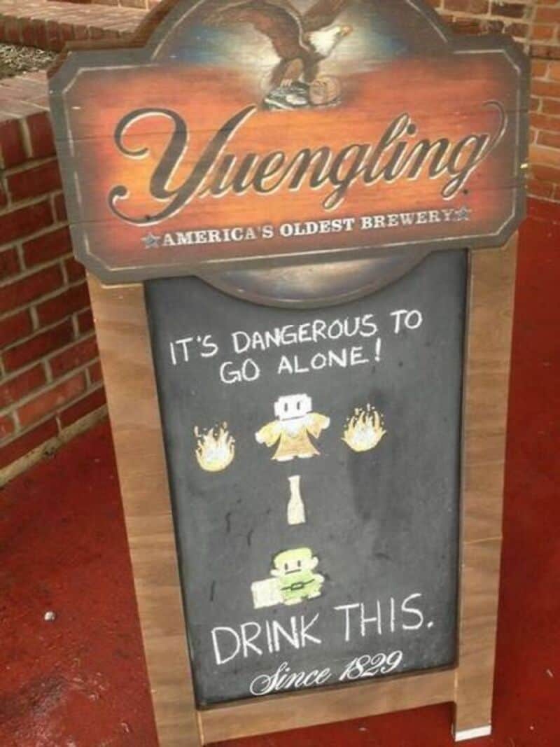 Yuengling sign with a chalkboard message about going alone and drinking since 1829.