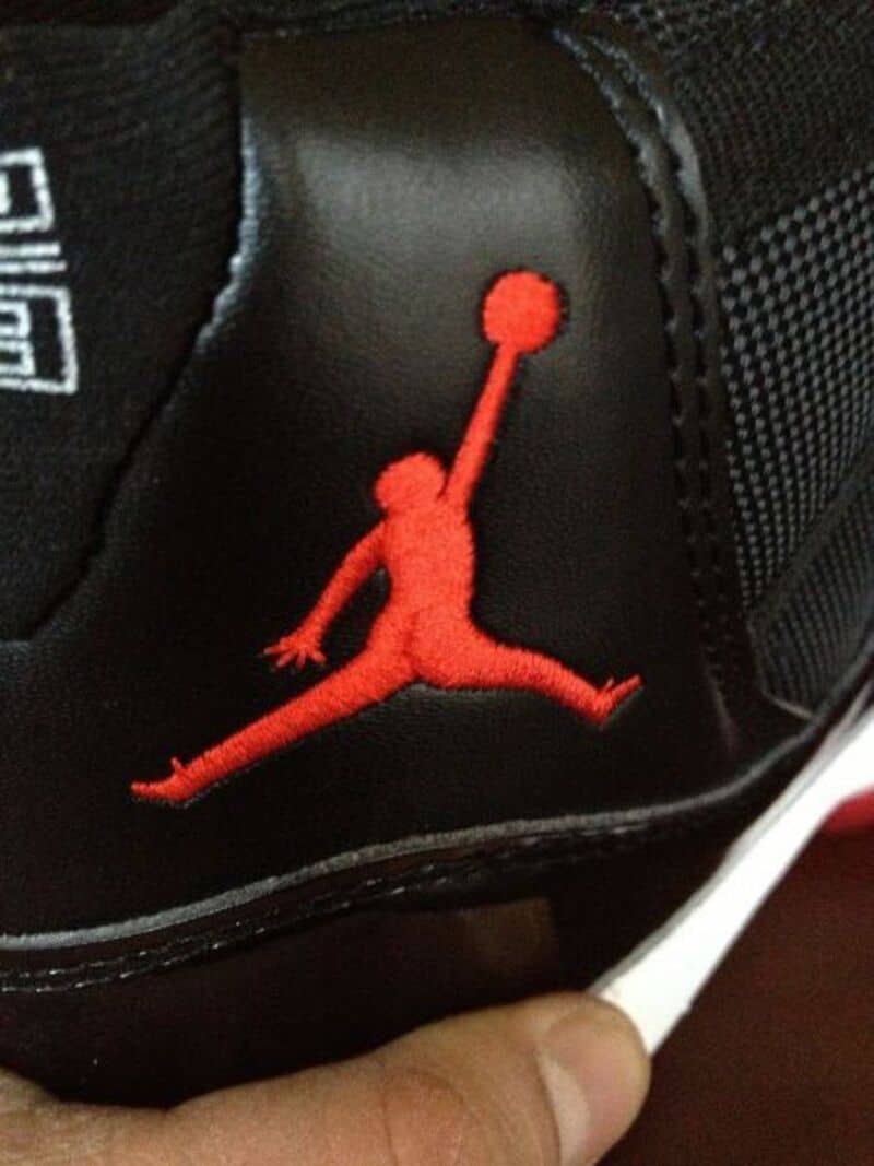 Close-up of a black shoe with a red Jumpman logo and a basketball in the air.