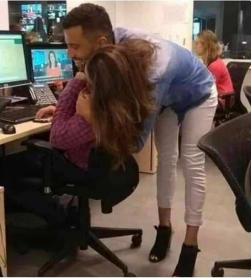 Woman leaning over to look at computer screen with man in office.