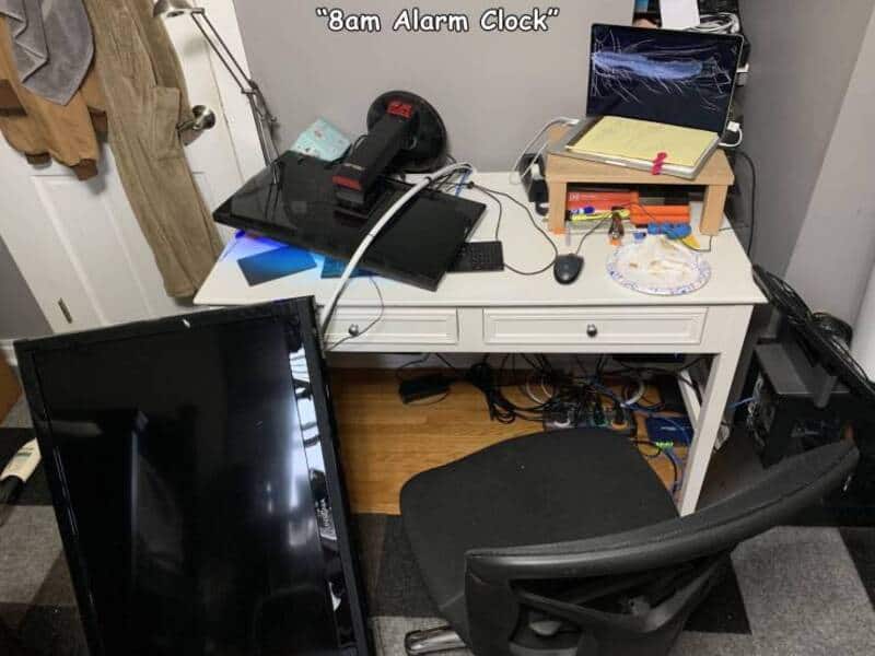 Cluttered desk with alarm clock, laptop, and various office supplies, titled '8am Alarm Clock'.