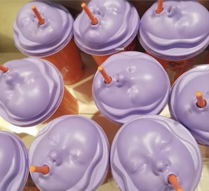 Purple drinks with orange straws in plastic cups, top view.
