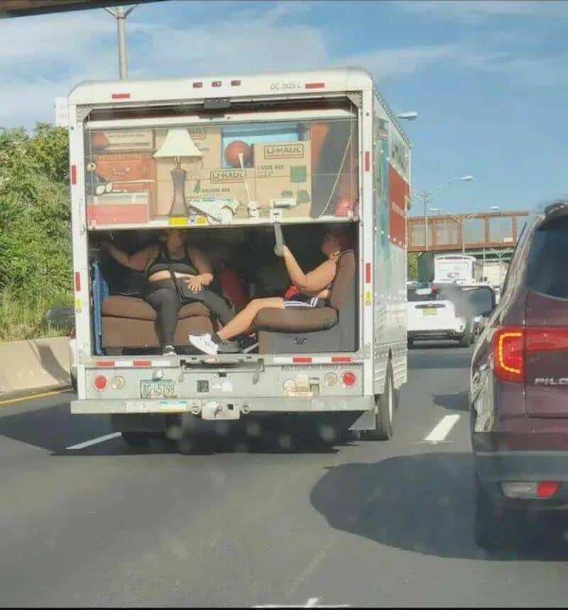 Two women in a U-Haul truck with the back open, one holding a baseball bat.