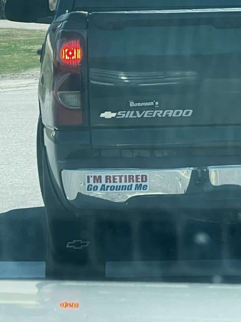 Rear of a Chevrolet Silverado with a bumper sticker that says "I'M RETIRED Go Around Me".