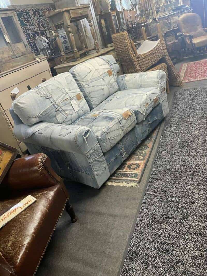 Worn-out light blue sofa with torn fabric and stuffing showing.