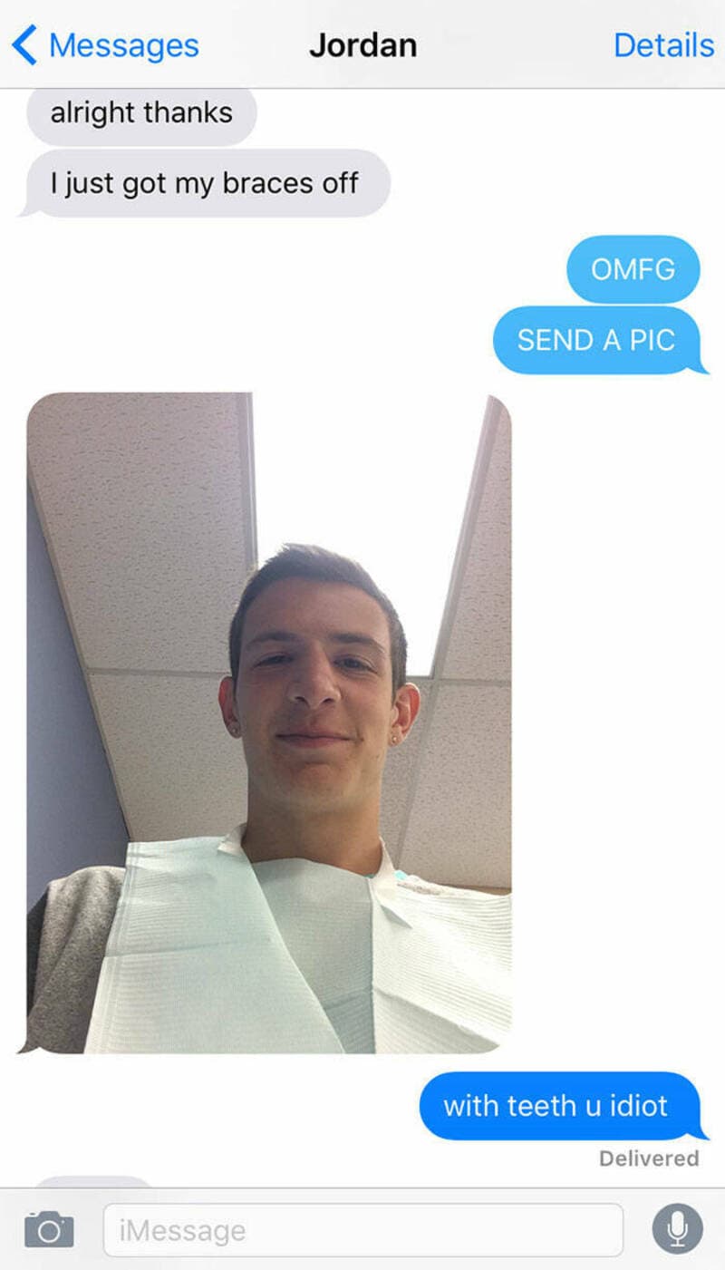 Young man in a hospital gown taking a selfie, smiling, with braces removed.