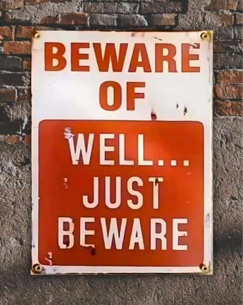 Beware of well... just beware sign on brick wall.