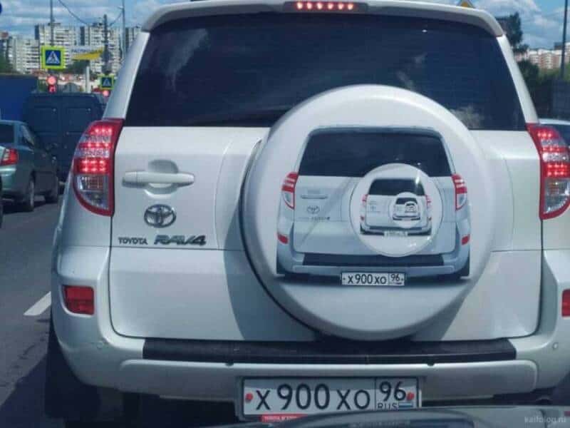White Toyota RAV4 with a spare tire cover showing a smaller image of the same car.