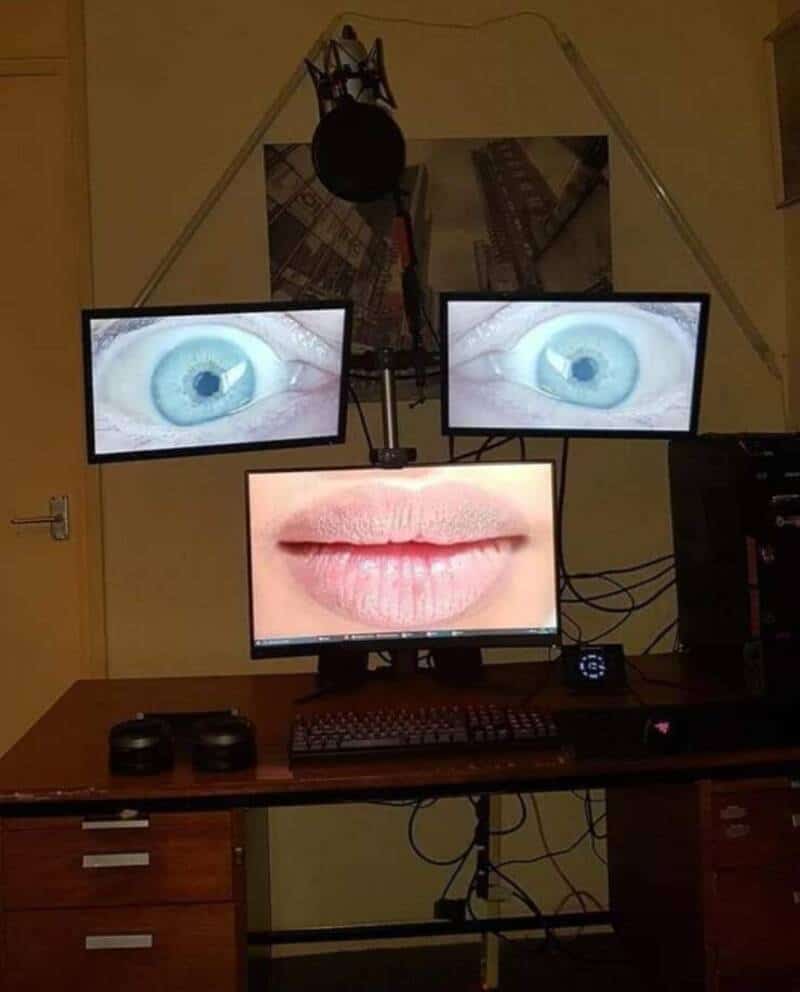 Three monitors display eyes and a mouth, creating a surreal face.