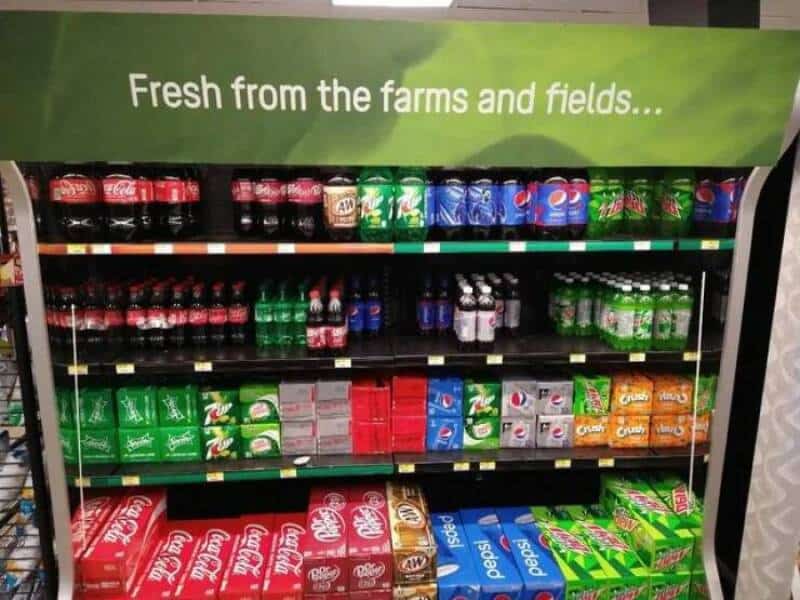 Display of various soda bottles with a green sign saying 'Fresh from the farms and fields...'.
