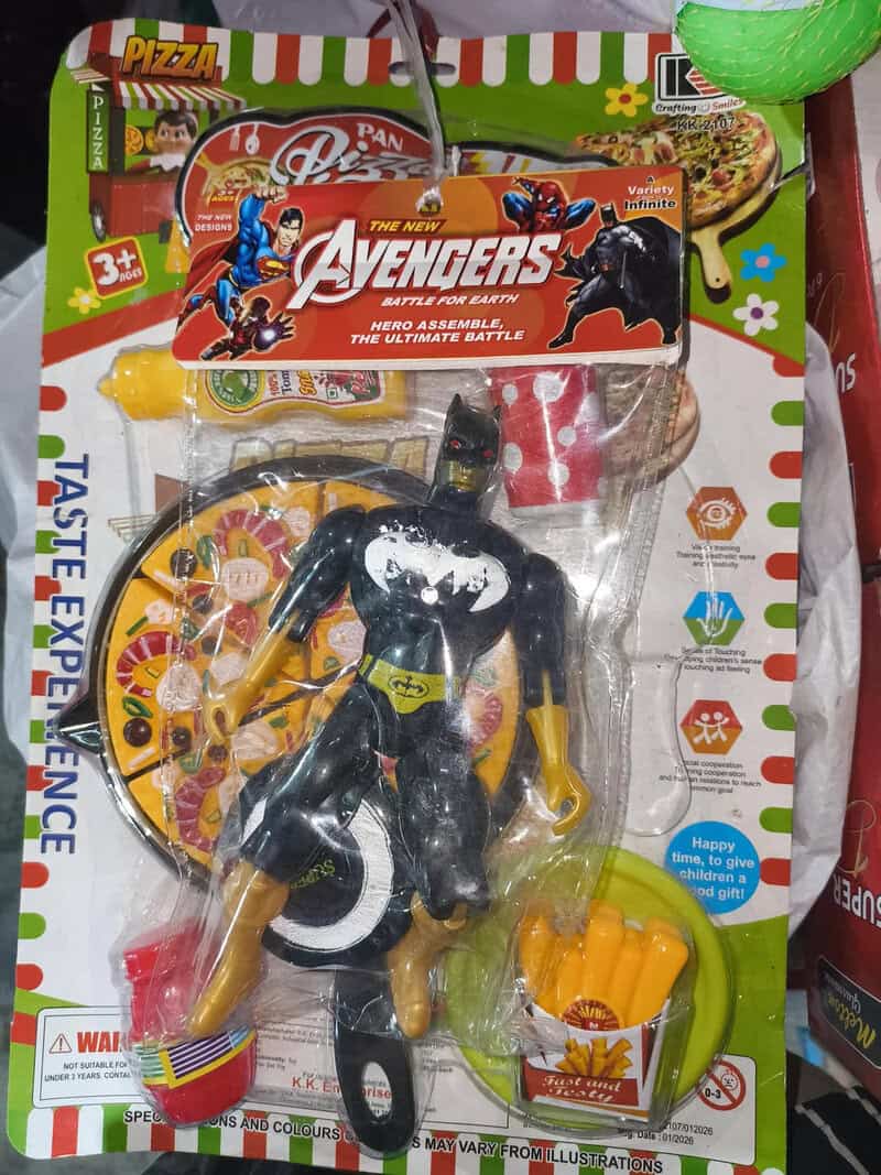 Toy Batman figure with a pizza and game in the background.