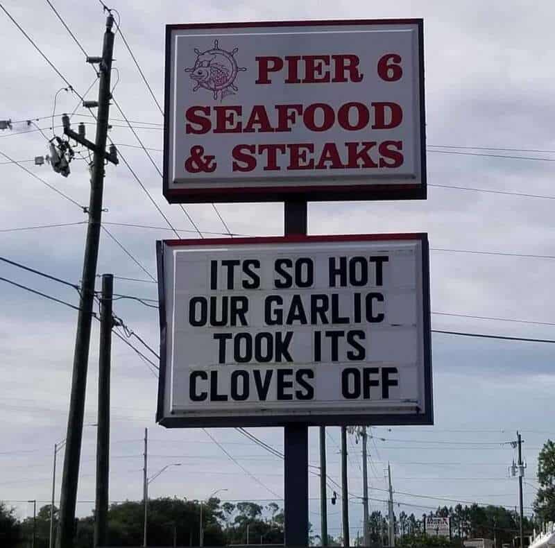 Sign for Pier 6 Seafood & Steaks with a humorous message about garlic and cloves.
