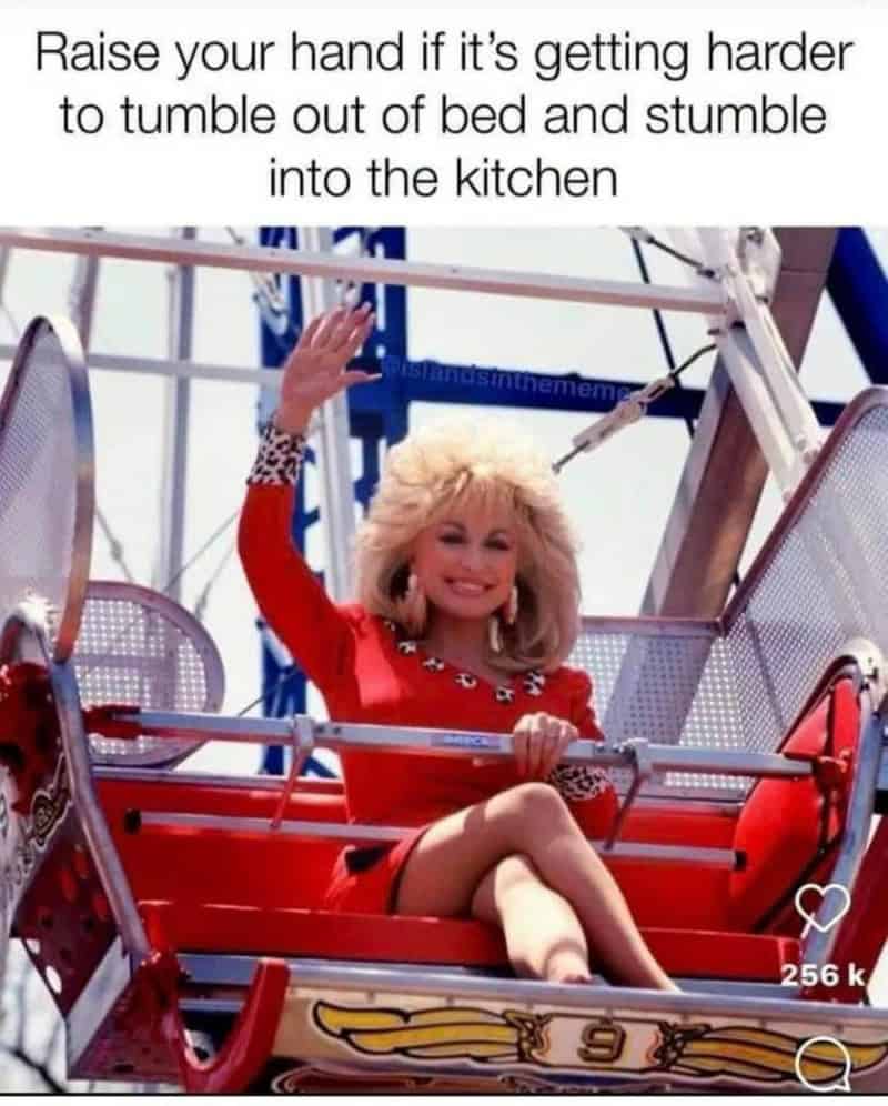 Woman with blonde hair in red dress on amusement park ride, raising hand.