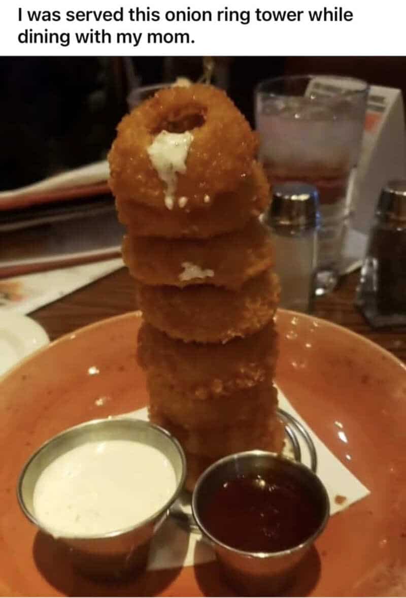 Stacked onion rings with dipping sauces, caption about onion ring tower at dinner.