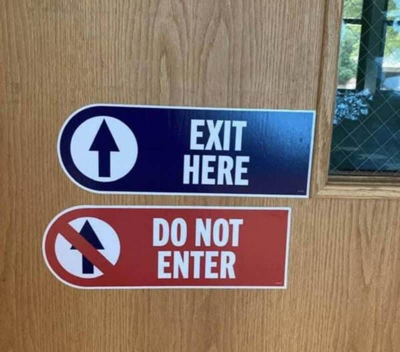 Exit here sign above Do Not Enter sign on wooden door.