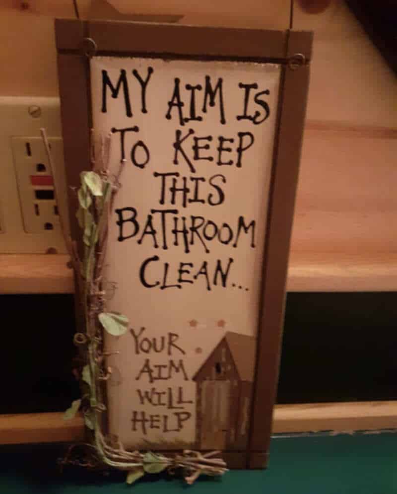 Sign reads 'My aim is to keep this bathroom clean... your aim will help' with a small house drawing.