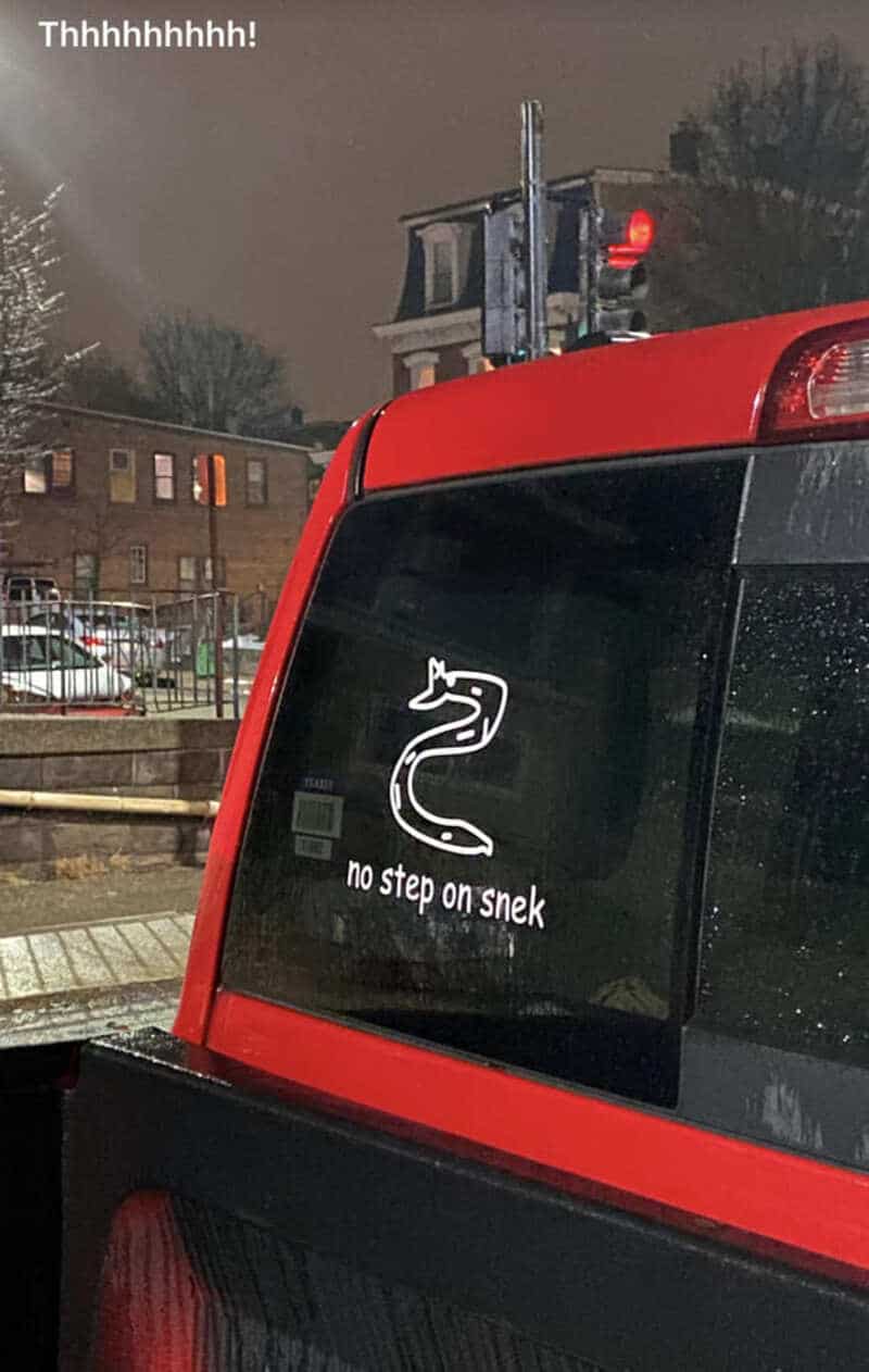 Red vehicle with a snake sticker and the text 'no step on snek' on the back window.