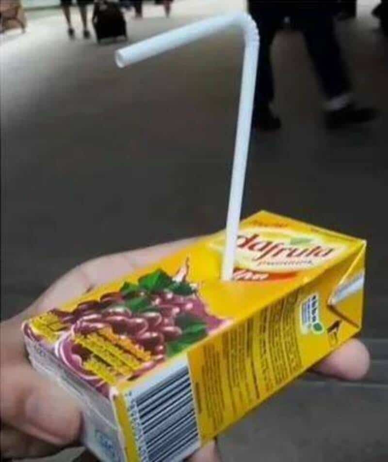 Juice box with a straw and a small plastic spoon on top.