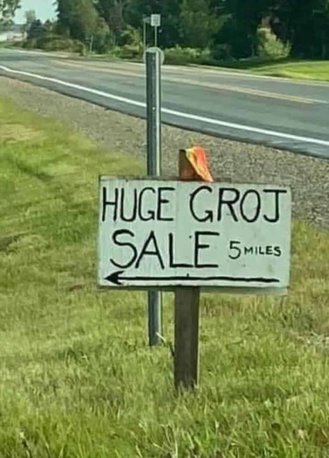 Sign on roadside advertising 'HUGE GROJ SALE 5 MILES' with misspelling of 'GROJ'.