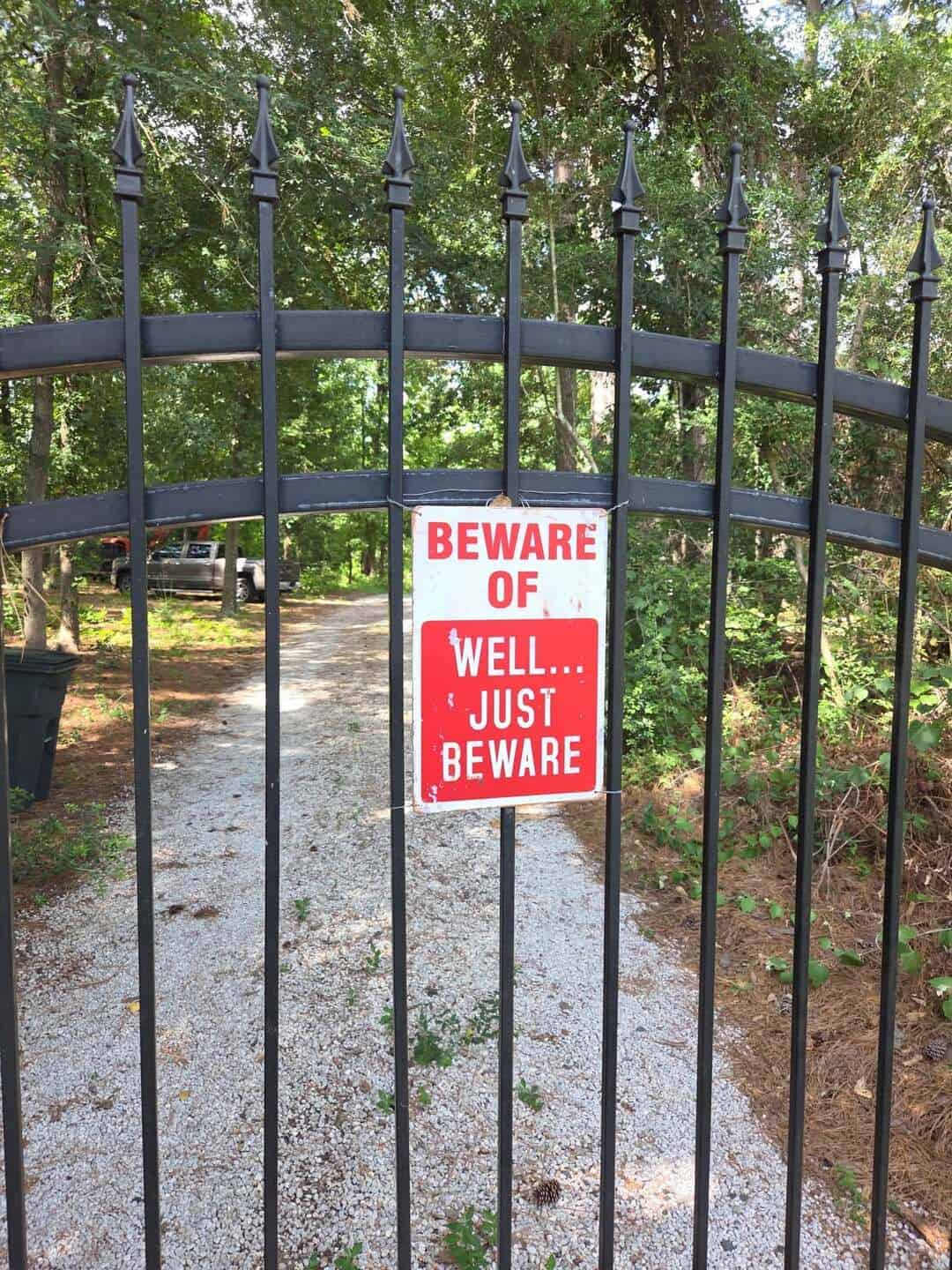 Beware of well... just beware sign on a black metal gate.