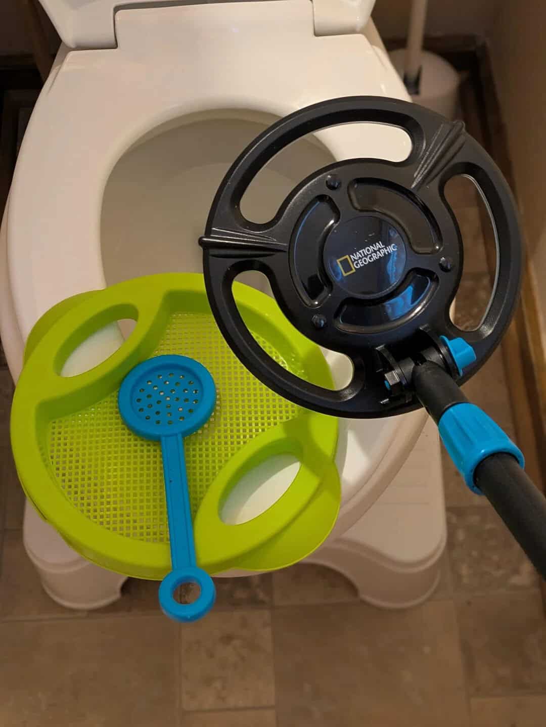 A toy steering wheel and a plastic scoop on a toilet seat.