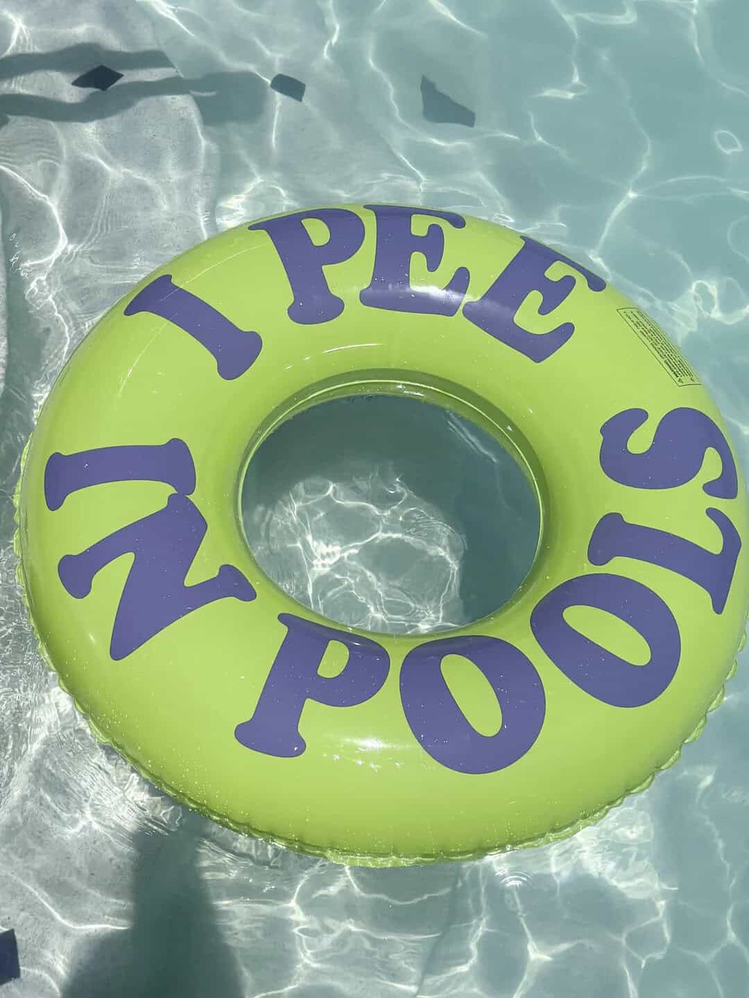 Inflatable pool float with 'NOPE' and 'I PEE' written on it in purple letters.