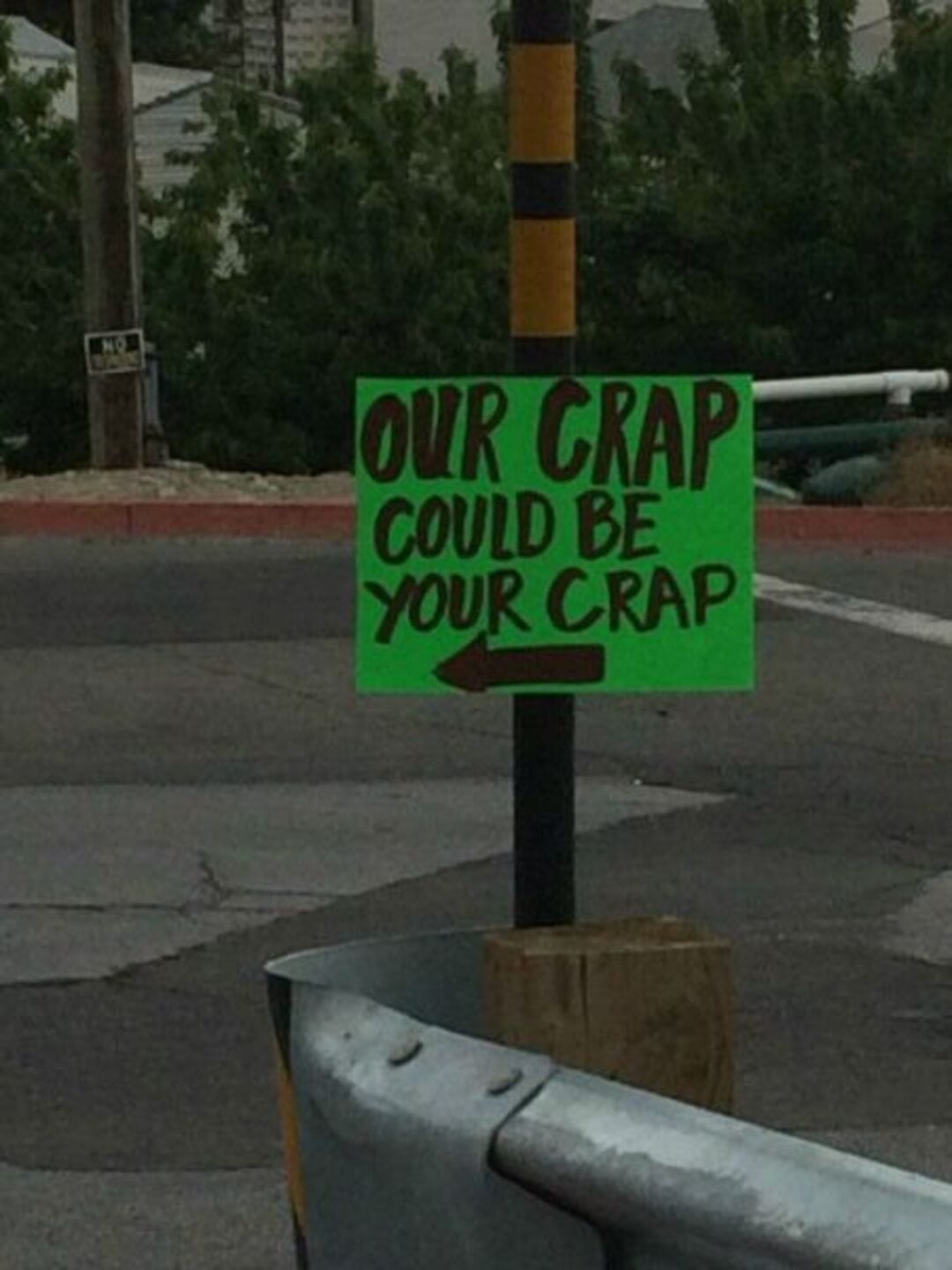 Sign reads 'OUR CRAP COULD BE YOUR CRAP' with an arrow pointing left.
