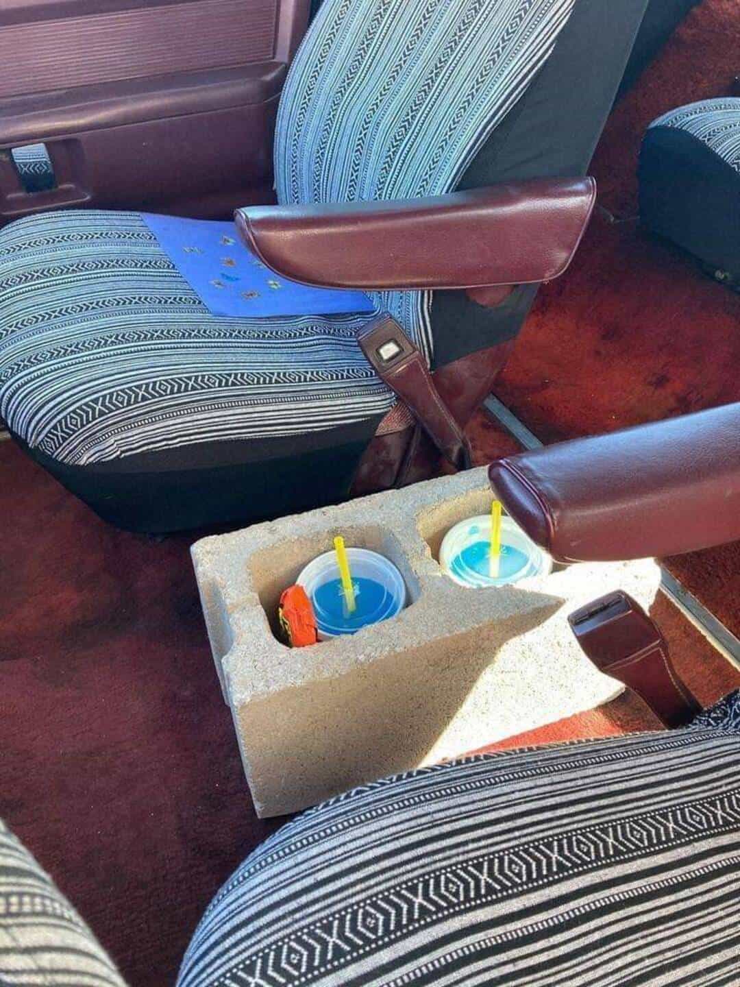 Two cups with straws in a foam container between bus seats.
