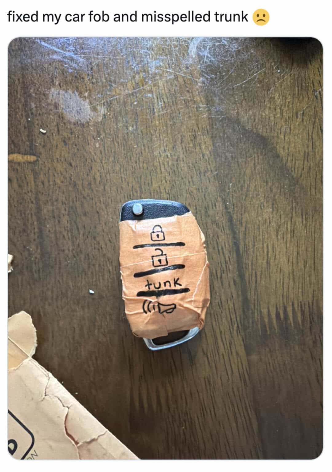 Car key with a paper cover labeled 'fix', 'misspelled trunk', and a sad face.