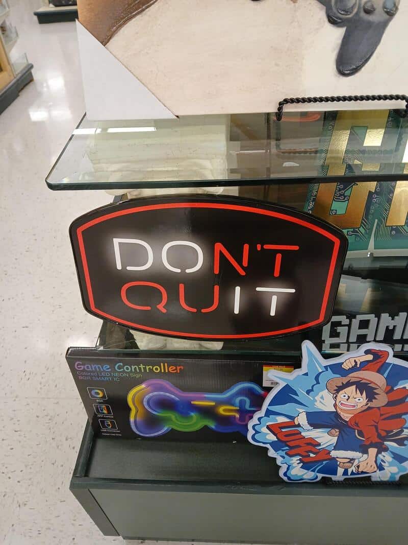 Sign says 'DON'T QUIT' with a game controller below it.