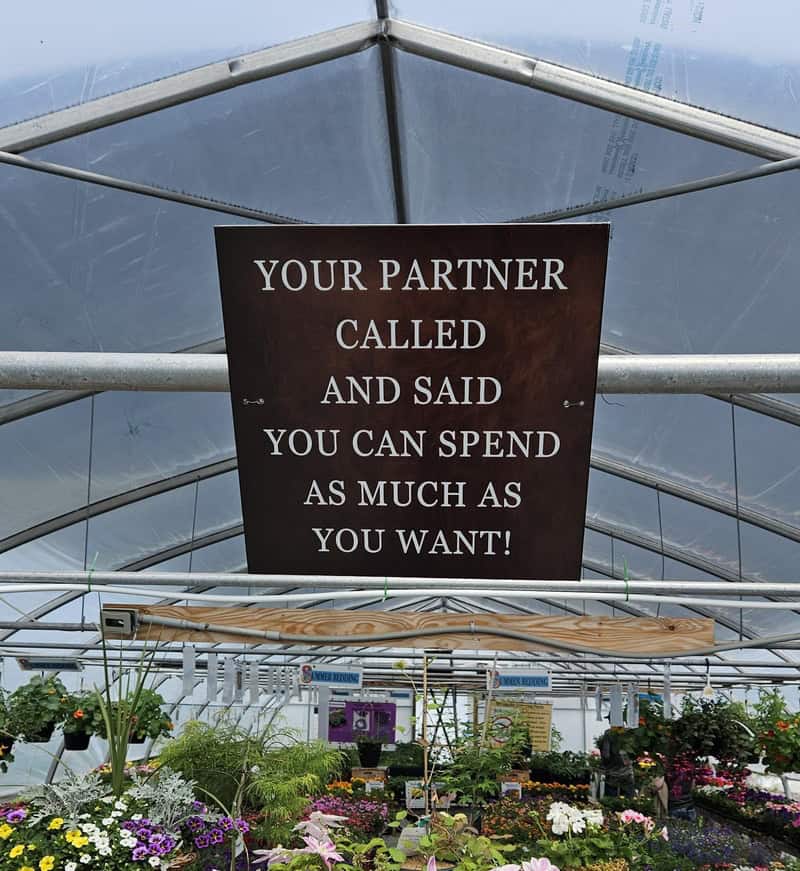 Sign in a greenhouse reads: 'Your partner called and said you can spend as much as you want!'.
