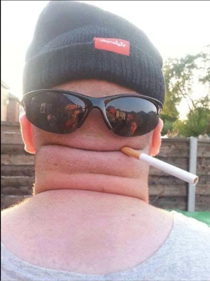 Person with sunglasses, beanie, and a cigarette in mouth, face distorted.