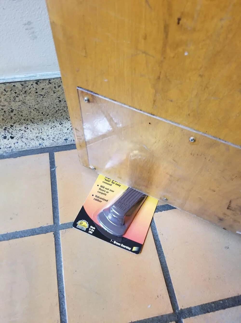 A card with a shoe print is stuck under a door, with a sign on the card.