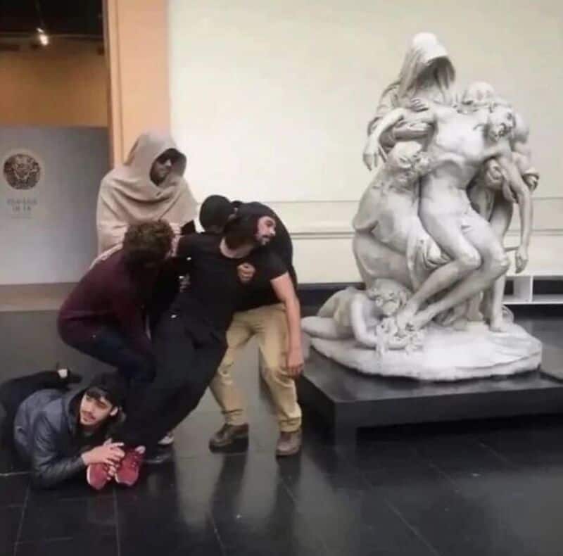 Group of five people posing near a classical sculpture in a museum.