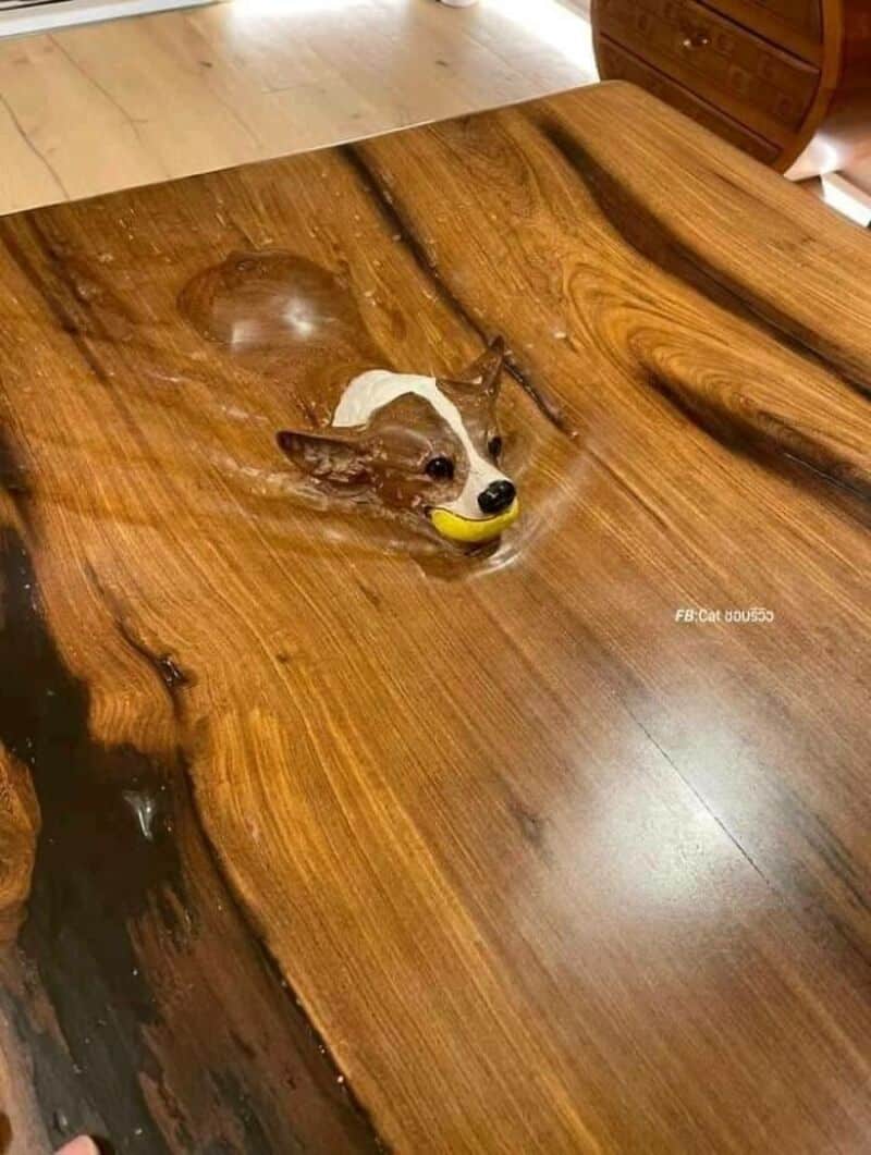 A dog figurine with a tennis ball in its mouth on a wooden table.