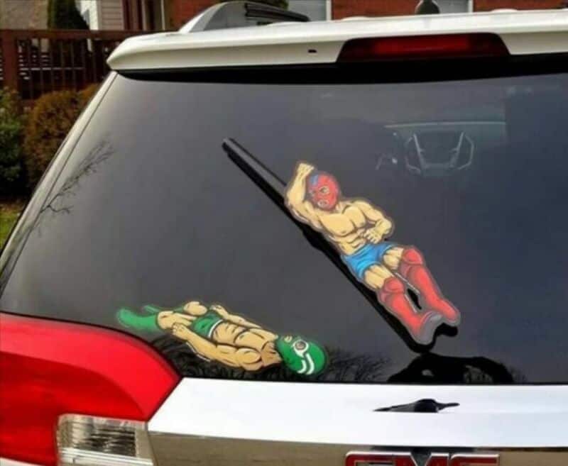 Car window decal of two cartoon characters, one with a gun and the other lying down.