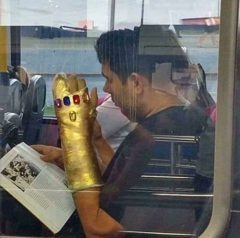 Person with a gold glove with colored stones, reading a book on a bus.