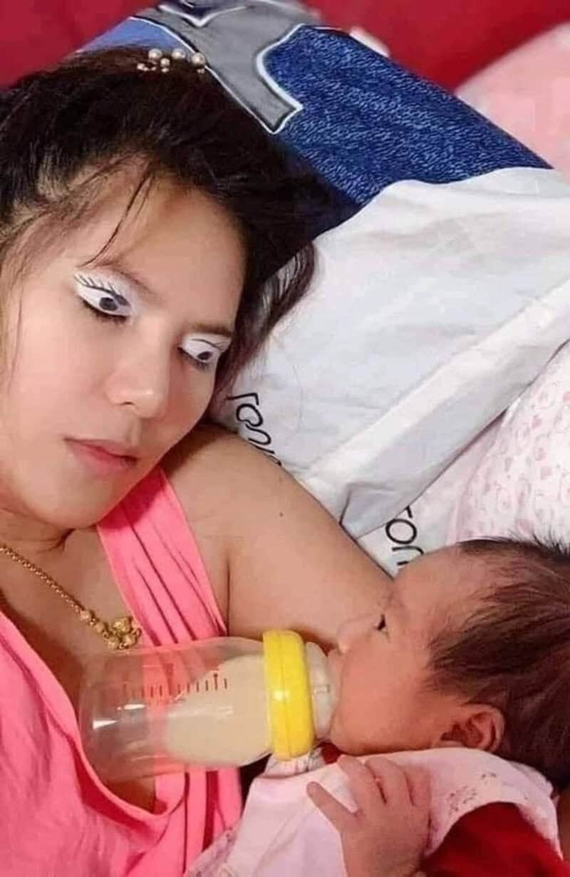 Woman feeding baby with bottle, lying on bed, close-up view.
