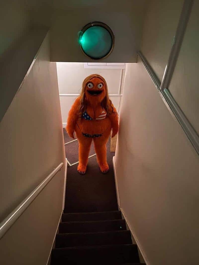 Large orange furry creature with big eyes and a bikini standing at the top of a staircase.