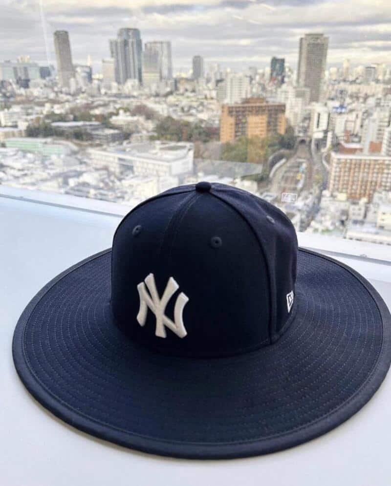 New York Yankees cap on a windowsill with city skyline in background.