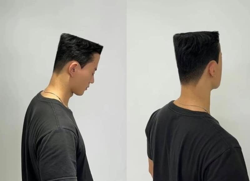 Side view of a young man with a fresh haircut, wearing a black t-shirt.