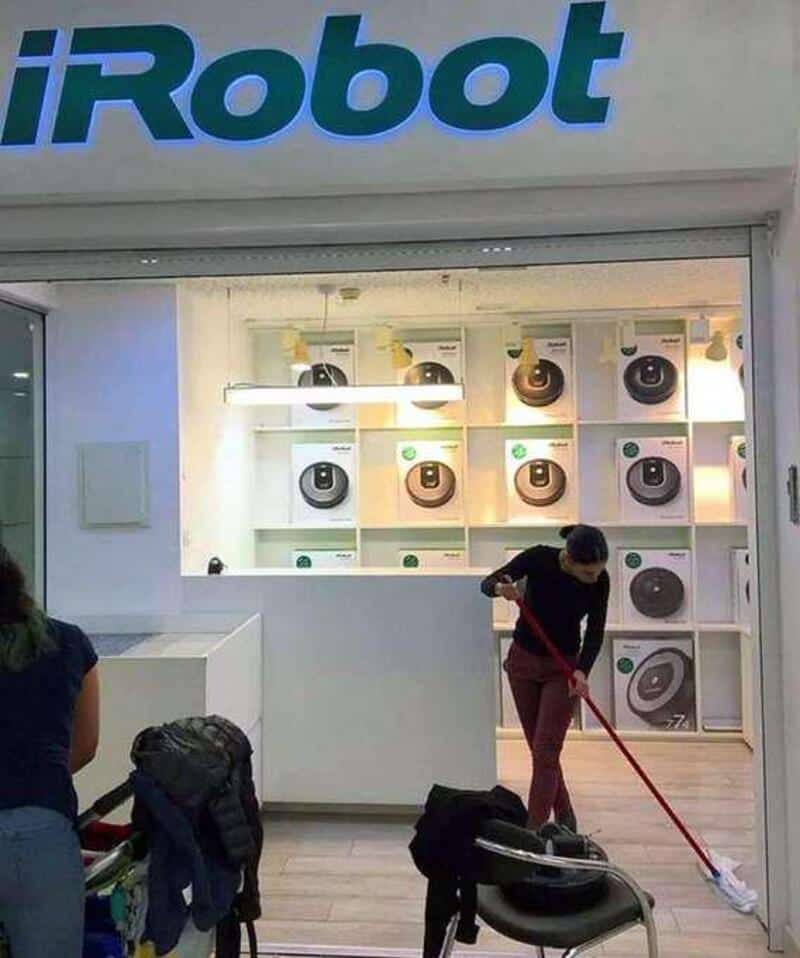 Child mopping store with iRobot logo in background.